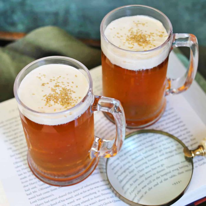 picture showing two mugs of homemade butter beer with foam top and gold sprinkles from a recipe by A Beautiful Mess